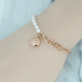 Elegante goudkleurige armband van titaniumstaal met witte parels en een smiley hangertje - Roségoud