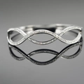 Polished silver infinity wave bangle with zircon inlay on a dark reflective surface - Silver