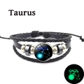 Détail macro du signe du zodiaque Taureau luminescent sur le bracelet tressé en cuir noir - Taureau - Lumineux