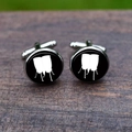 Close-up of silver-tone cufflinks featuring white conga drum silhouettes on wood surface - Conga Drums Style