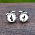 Silver round cufflinks with black treble clef and musical notes on a wooden table - Treble Clef Style