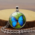 Dettaglio di un ciondolo cabochon in vetro argentato con farfalla su legno - Stile Farfalla Blu Viola / Argento