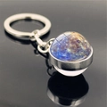 Macro shot of double-sided glass galaxy pendant keychain with blue-purple nebula design - Mercury