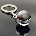 Macro shot of Pluto planet keychain with polished silver metal ring on reflective black surface - Pluto (PSXL001134-9)
