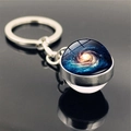 Macro shot of double-sided glass galaxy pendant keychain with blue swirling nebula - Blue-Black-Yellow Spiral Galaxy Style (PSXL001466-8)