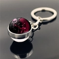 Macro view of Virgo constellation glass ball keychain with silver metal ring on black reflective base - Virgo (XSWX2268-10)