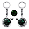 Detail of a rotating silver Sagittarius zodiac keychain with a luminous green moon pendant - Sagittarius