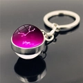 Macro shot of Virgo zodiac glass ball pendant with purple nebula design on metal keychain - Virgo