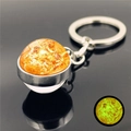 Detail showing glowing solar sun galaxy glass ball keychain on reflective surface - Sun