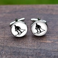 Detailed view of silver ski silhouette cufflinks on dark wood texture background - Skiing Silhouette (5HXK0100-7)