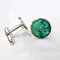 Macro detail of round peacock feather cufflinks with a polished silver-tone metal finish - Silver