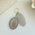Macro detail of portable silver glitter folding comb and mirror keychain for handbags - Glittery Grey