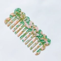 Macro view of green floral cellulose acetate hair comb with wavy edges and smooth teeth - Pink & Green