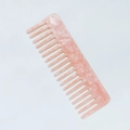Vista macro del pettine a denti larghi con trama in acetato marmorizzato rosa e punte - Rosa