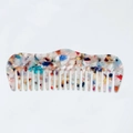 Détail d'un peigne en acétate à motif marbré avec de larges dents lisses sur fond blanc - Arc-en-ciel