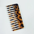 Primo piano di un pettine a denti larghi in acetato tartarugato con motivi ambrati lucidi - Stampa leopardata