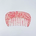 Macro view of pink marble acetate wide-tooth hair comb with smooth curved design - Pink Snowflake