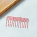 Pink and white marble acetate wide-tooth hair comb on a minimalist white and wood background - Rectangle