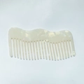 Dettaglio macro dell'elegante pettine in acetato bianco perla a denti larghi con onde - Colore Sirena