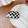 Modische schwarz-weiße Haarklammer mit Karomuster aus Acetat auf einem weißen Keramikteller - Black White Checkerboard Claw Clip