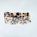 Dettaglio del pettine in acetato a denti larghi con motivo tartarugato e dorso ondulato - Leopardo Chiaro