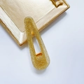 Barrette goutte évidée à paillettes dorées posée sur une assiette dorée - Goutte-Jaune