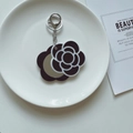 Macro view of portable camellia flower keychain mirror with silver metal clasp - Black Base Camellia Mirror
