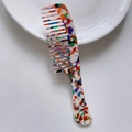 Detail van een kleurrijke marmeren acetaat kam met brede tanden op een wit bordje - Acetaat 17.8cm*4.2cm*3mm / Regenboog