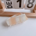 Detail of large rectangular orange marble acetate hair claw with gold Barrette lettering - Irregular Geometry Claw Clip