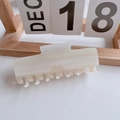 Detail view of large cream acetate hair claw clip with marble texture and logo - Large Rectangular Claw Clip