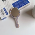 Close-up of a handheld floral acetate mirror with marble textures on a book - 12.5cm*5.8cm / Purple