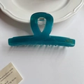 Detailed close-up of dark teal translucent acetate hair claw with gold lettering text - Green
