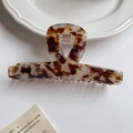 Close-up of leopard pattern hair claw made of high-quality acetate with gold logo detail - Coffee White