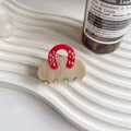 Dettaglio molletta per capelli in acetato beige con manico rosso su vassoio ondulato - Beige