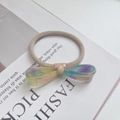 Detailed macro view of an iridescent resin bow hair tie on a white magazine background - Iridescent Yellow