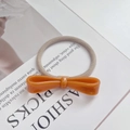 Slim khaki elastic hair tie with orange acetate bow and gold label detail - Caramel color
