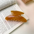 Dettaglio del fermaglio per capelli in acetato ambra con testo su un libro aperto - Ambra-9.5cm*4cm 22g