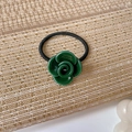 Dettaglio dell'elastico per capelli a camelia in acetato verde con scritta dorata - verde scuro