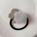 Detail of plush rabbit hair tie with grey faux fur, gold studs, and pearl accents - Gray