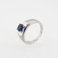 Elegante anillo de plata con un zafiro azul redondo central y un engaste de cuatro garras - Estilo Zafiro Arenado