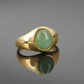 Minimalist gold titanium steel ring with an oval green tiger eye stone on a grey surface - Gold Base Aventurine