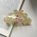 Detalle macro de la pinza de pelo flor de acetato irisado con marca grabada France en libro - Rosa y Verde