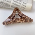 Detailed macro of a large acetate triangle hair claw clip with tortoise shell marble patterns - Coffee Texture