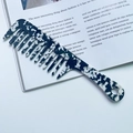 Detail of marble pattern acetate wide-tooth comb with geometric handle on magazine - Cow Pattern