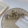 Detailed view of a marble pattern acetate hair claw clip on a minimalist ceramic plate - Gray White