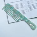 Mint green marble acetate wide-tooth hair comb with geometric long handle on magazine - Cyan