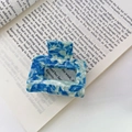 Detail view of blue and white marble acetate square hair claw clip on book pages - Blue Marble