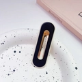 Gros plan d'une pince à cheveux minimaliste bleu marine et crème sur un plateau à pois - Noir-Ovale Creux