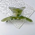 Detail of elegant fishtail hair claw clip in green marble acetate with secure metal spring - Green