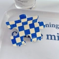 Gros plan d'une pince à cheveux en forme de puzzle avec motifs à damier bleu et blanc - Bleu